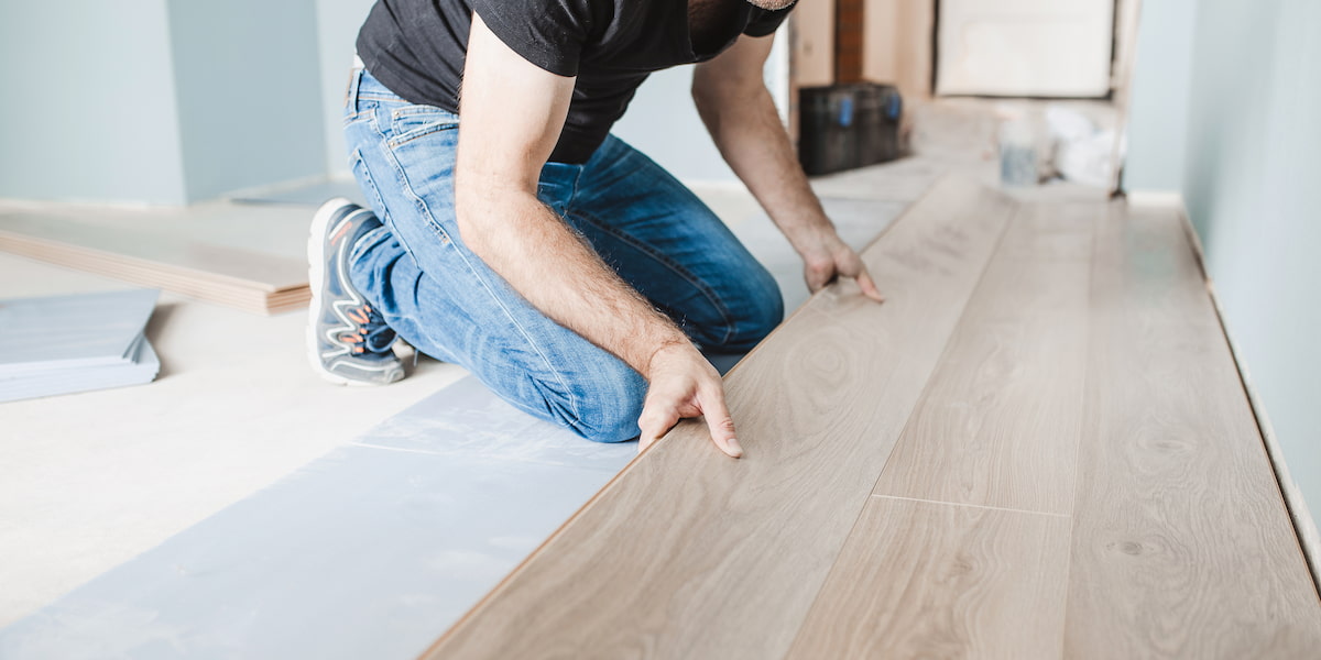 A worker installing vinyl flooring, demonstrating best practices for how to protect vinyl flooring from scratches during and after installation.