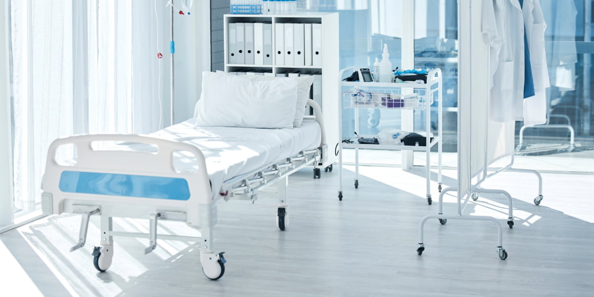 Modern patient room with natural light, medical equipment, and durable hospital floors designed for safety, hygiene, and daily use