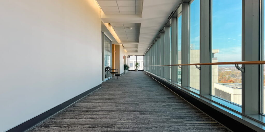 Wide hallway in a modern medical building with hospital grade carpet and floor-to-ceiling windows