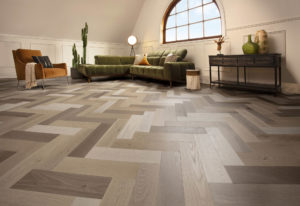A living room with a wooden floor and a couch featuring the Herringbone Collection
