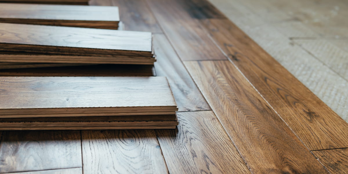 Stacks of wooden planks ready for installation, showcasing different hardwood floors in various tones and finishes for a seamless flooring transition.