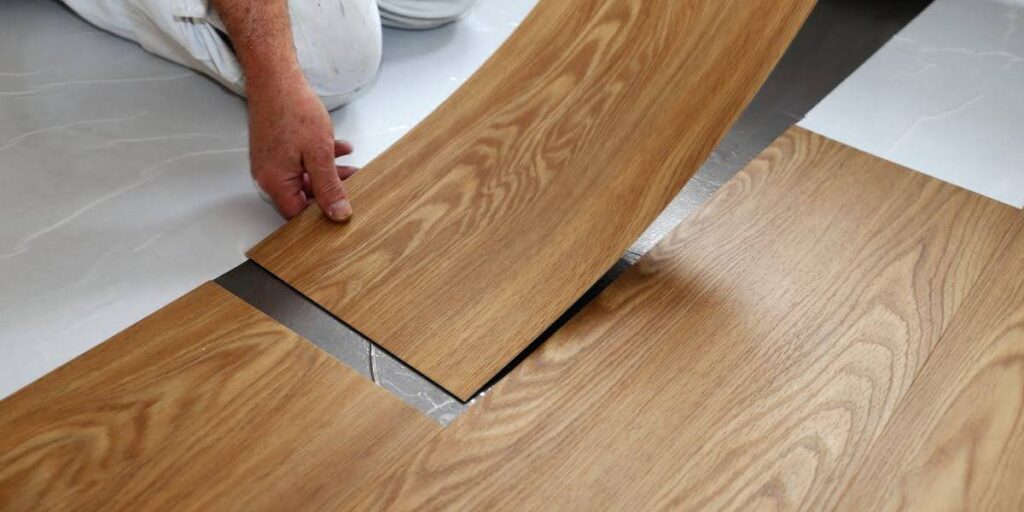 Close-up of worker installing commercial vinyl flooring planks in a modern space, highlighting durability and ease of installation.