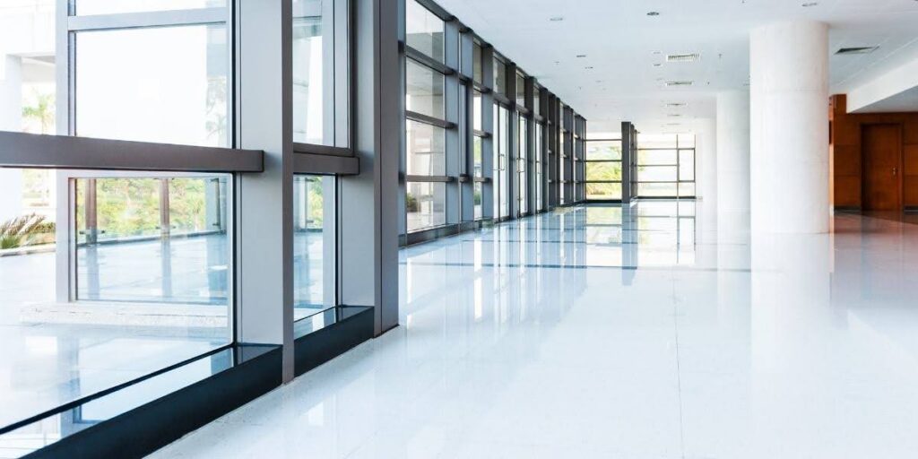 Bright, modern commercial space with glossy tile floors and large windows, showcasing Commercial Office Flooring in a contemporary office building.