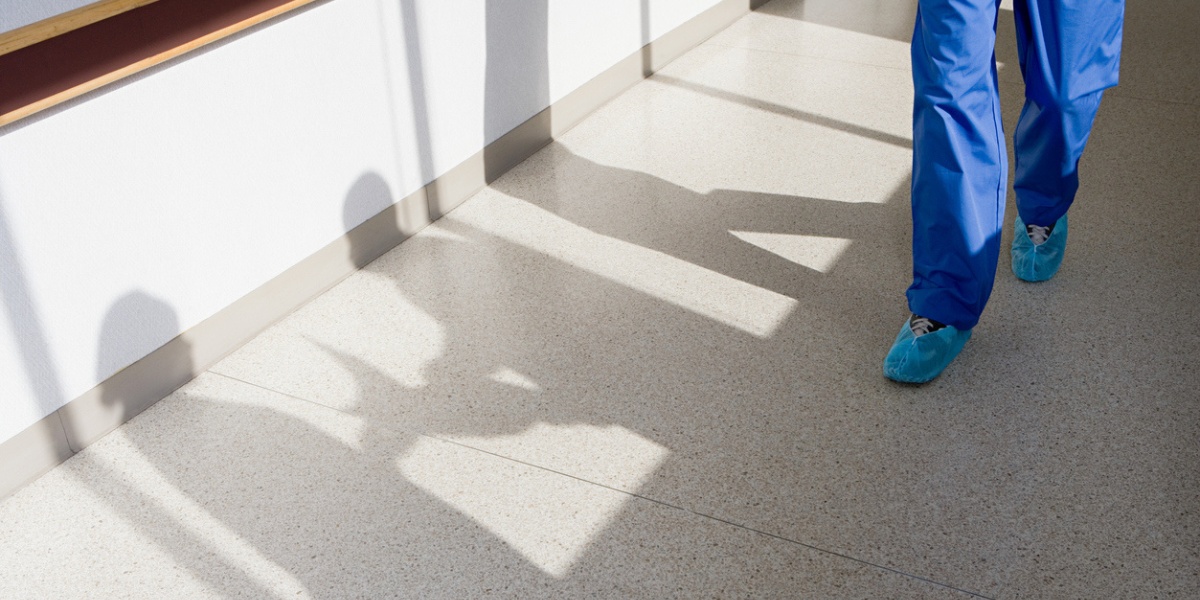 A healthcare worker walks on tile flooring for healthcare facilities.