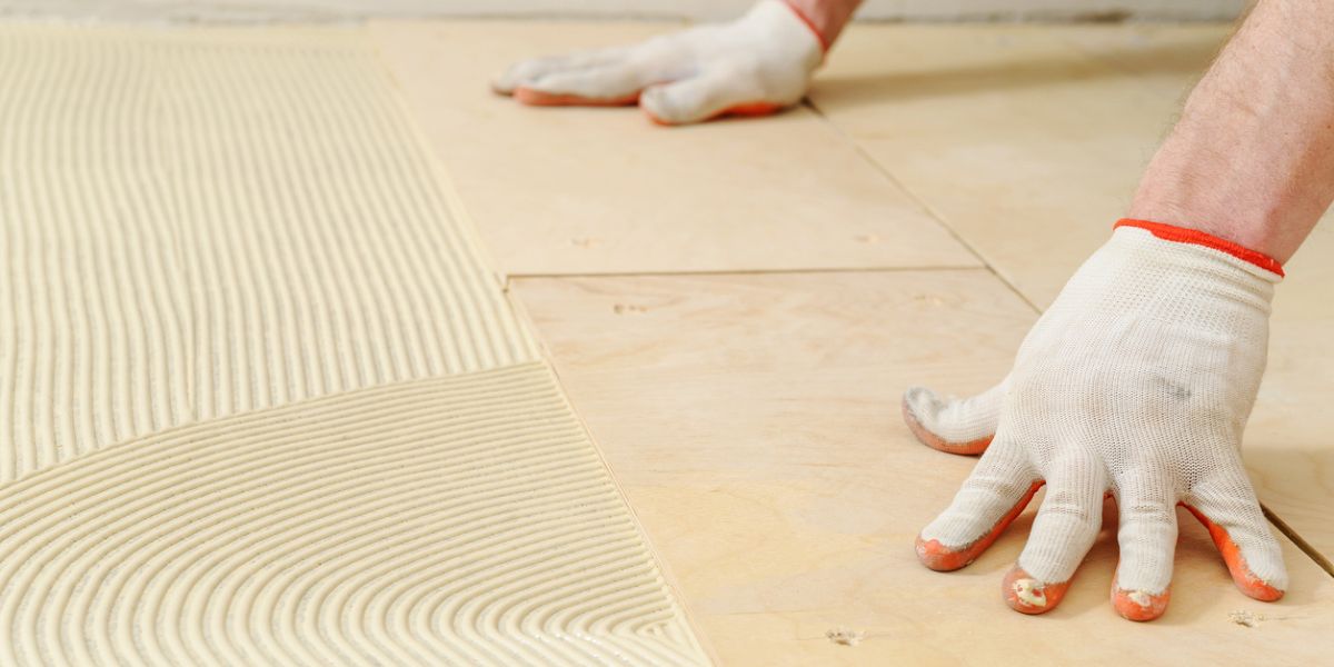 A worker is installing fresh subfloor after a subfloor replacement job for a residential home.