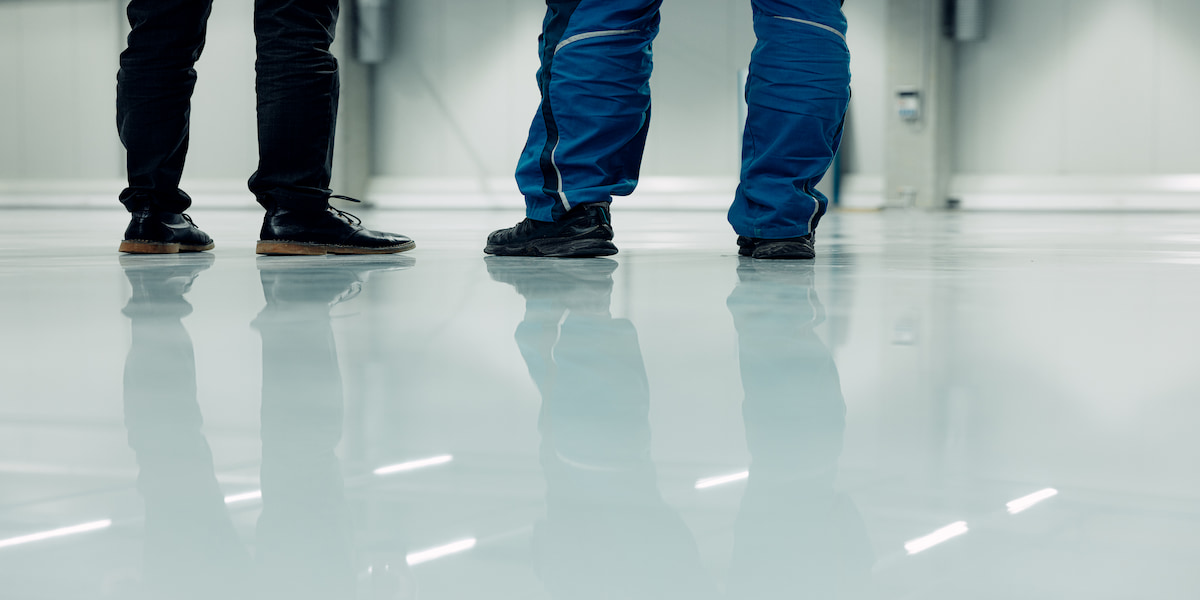 Close-up of three individuals standing on a glossy, durable floor, highlighting the high-quality finish. Image conveys an example of a strong and wear-resistant surface, addressing the question 'what is the most durable flooring?'