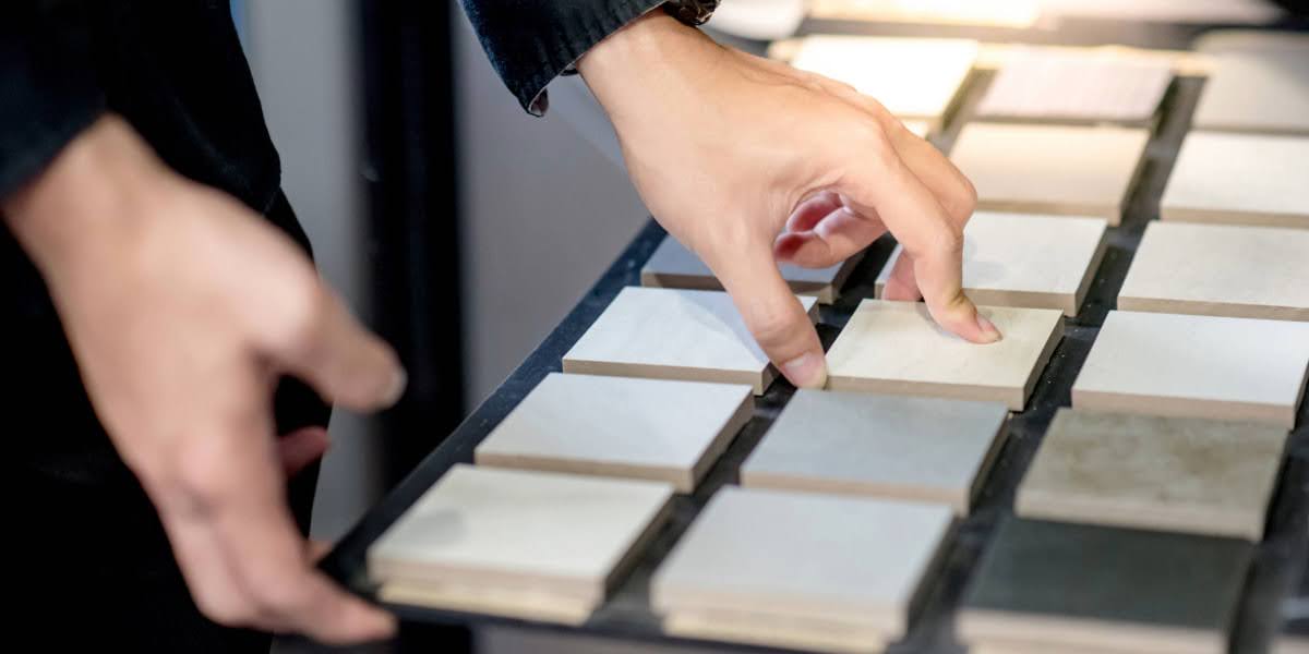 Person selecting commercial tile samples in a showroom, referencing ntca guidelines for proper material standards