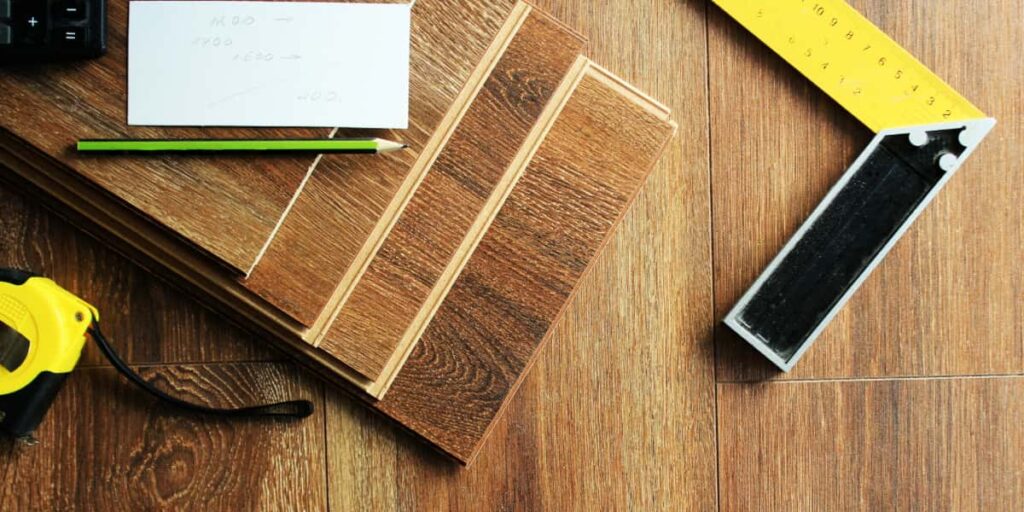 Wood flooring samples with measuring tools, tape measure, and notes on a table, representing flooring certifications and standards in commercial projects.